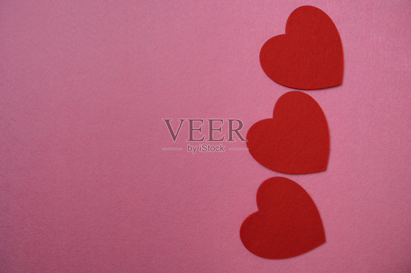 粉色背景上的红色毛毡心形装饰照片摄影图片