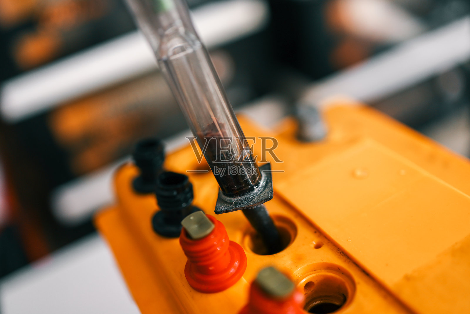 一个比重计用于测试黄色汽车电池的液体密度。电池上有明显的红色和黑色接头。照片摄影图片