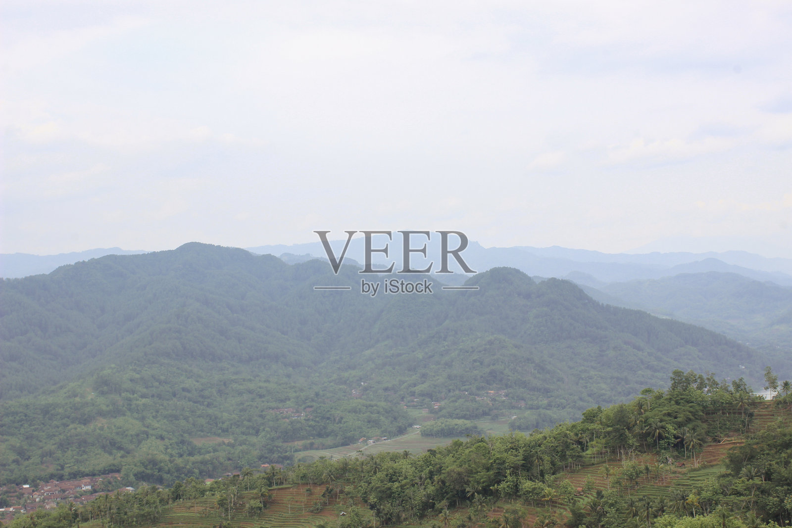 蓝天下的多云风景山丘与生机勃勃的绿色森林照片摄影图片