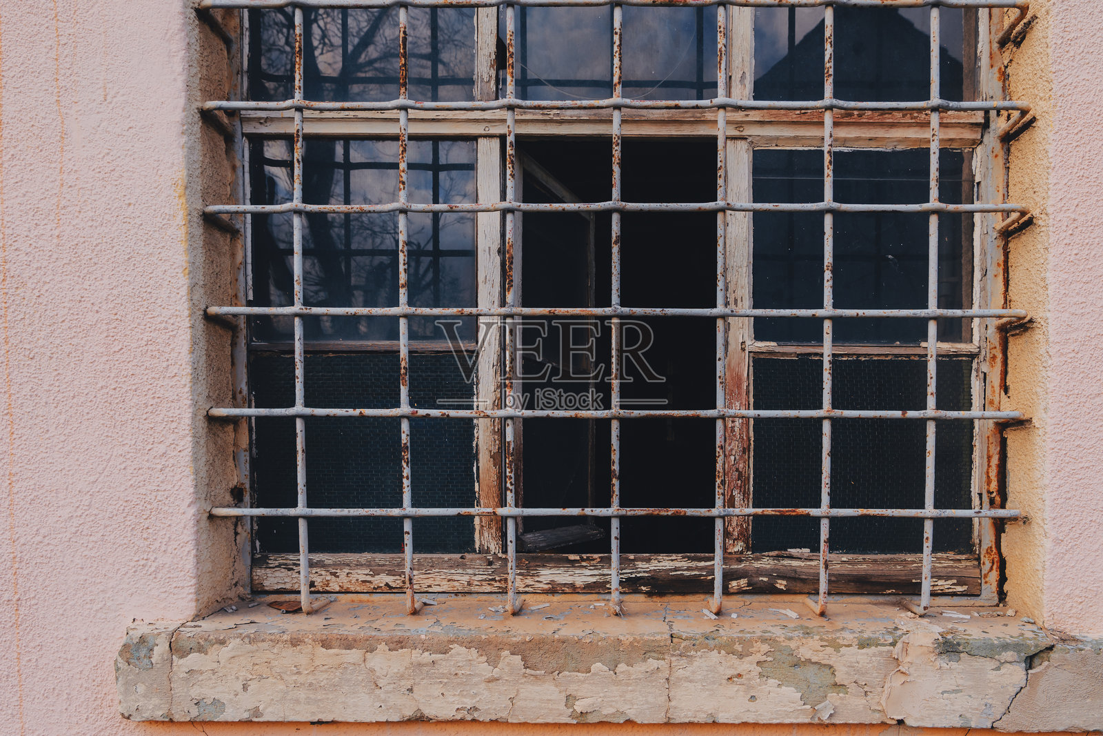 生锈的铁栅窗位于一座老建筑上，展示了城市环境中的磨损和衰败。照片摄影图片