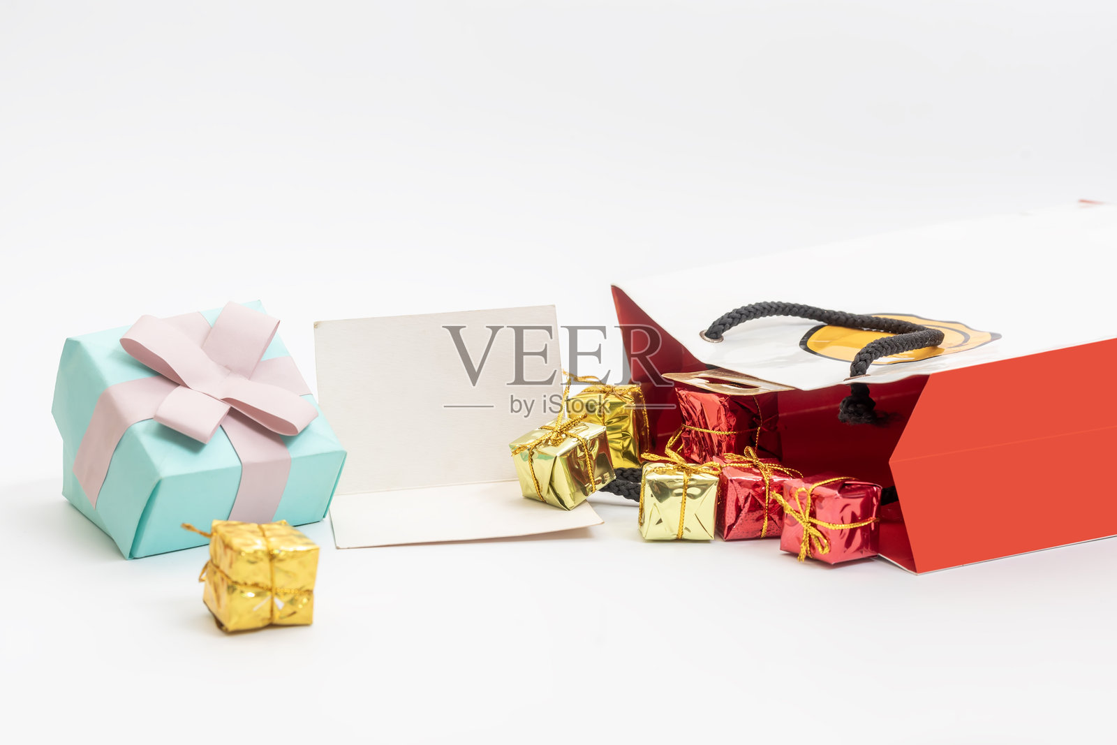 五颜六色的礼品盒和袋子，旁边有一张空白卡片，背景为白色。照片摄影图片
