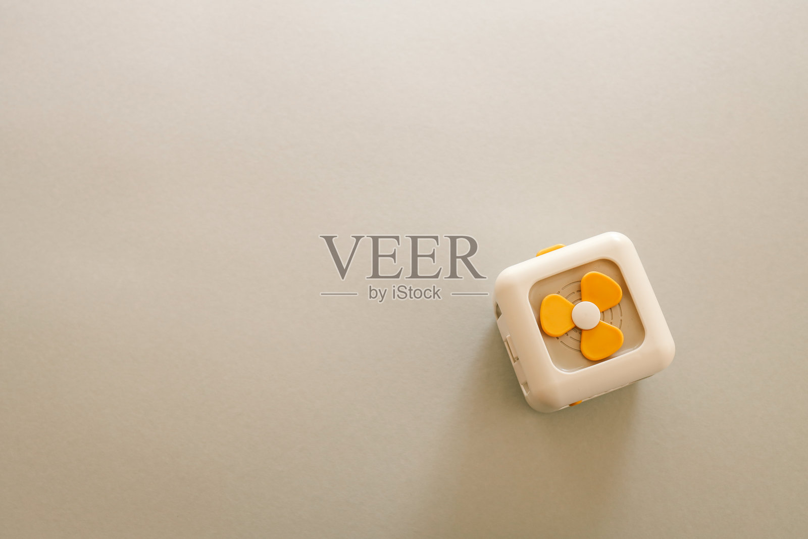 简约的玩具立方体，带有黄色螺旋桨设计，背景为浅米色，强调简约和现代美学照片摄影图片