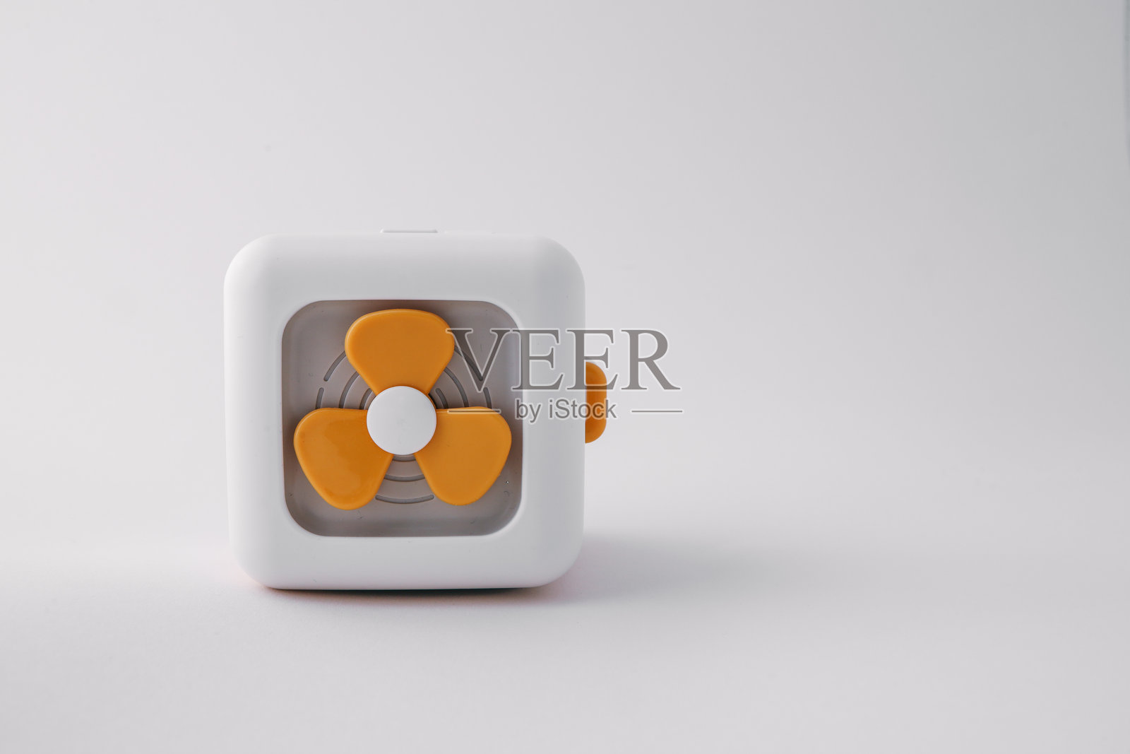 简约的白色立方体玩具风扇，橙色扇叶，背景干净白色。现代而富有趣味的设计，强调简单与创意。照片摄影图片