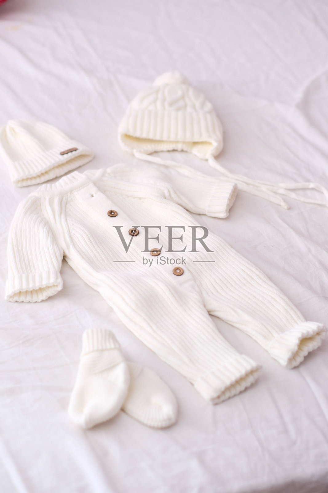 舒适温暖的白色针织婴儿服装，配有帽子和袜子。照片摄影图片