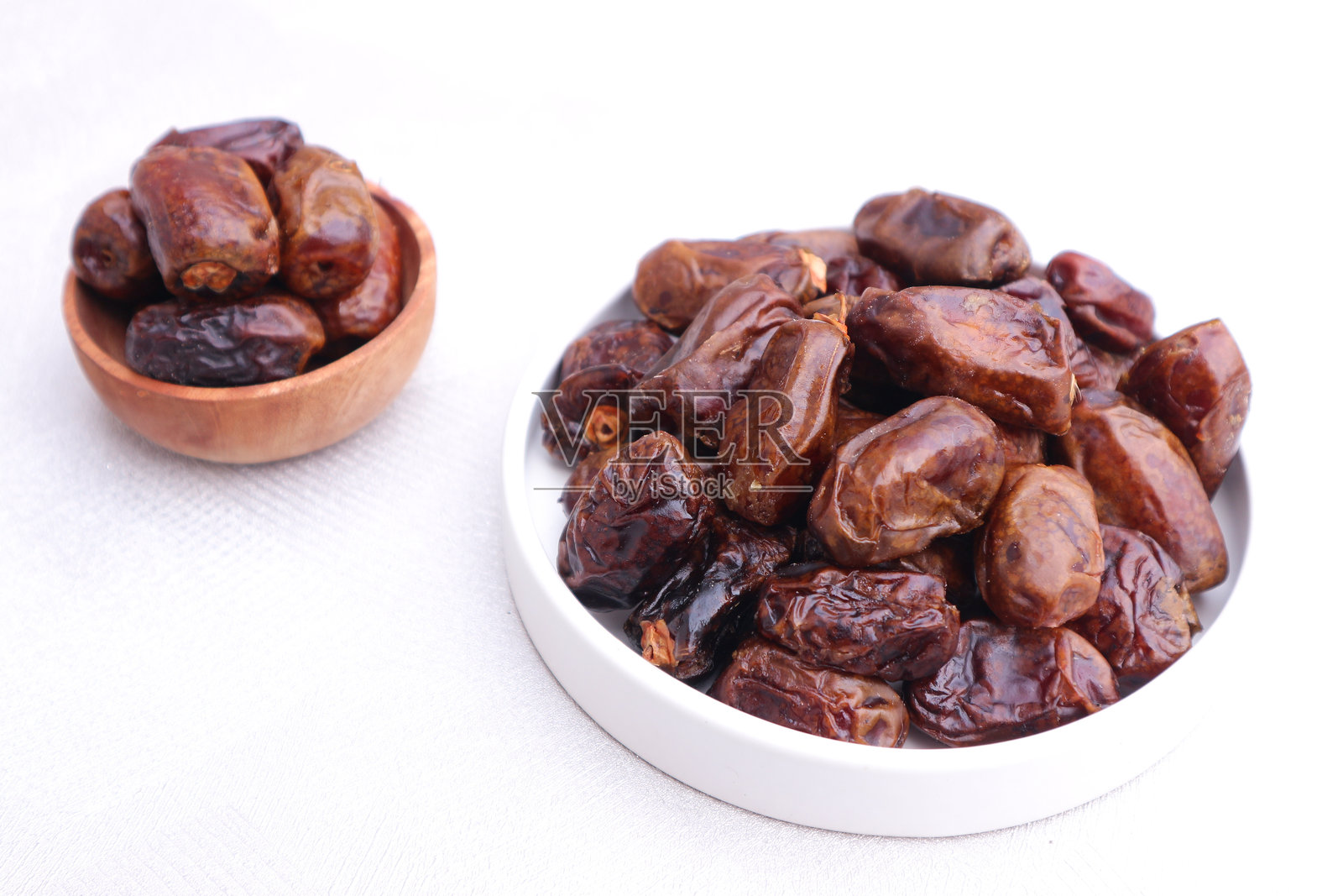 碗中的甜枣：白色表面上的干枣特写视图照片摄影图片
