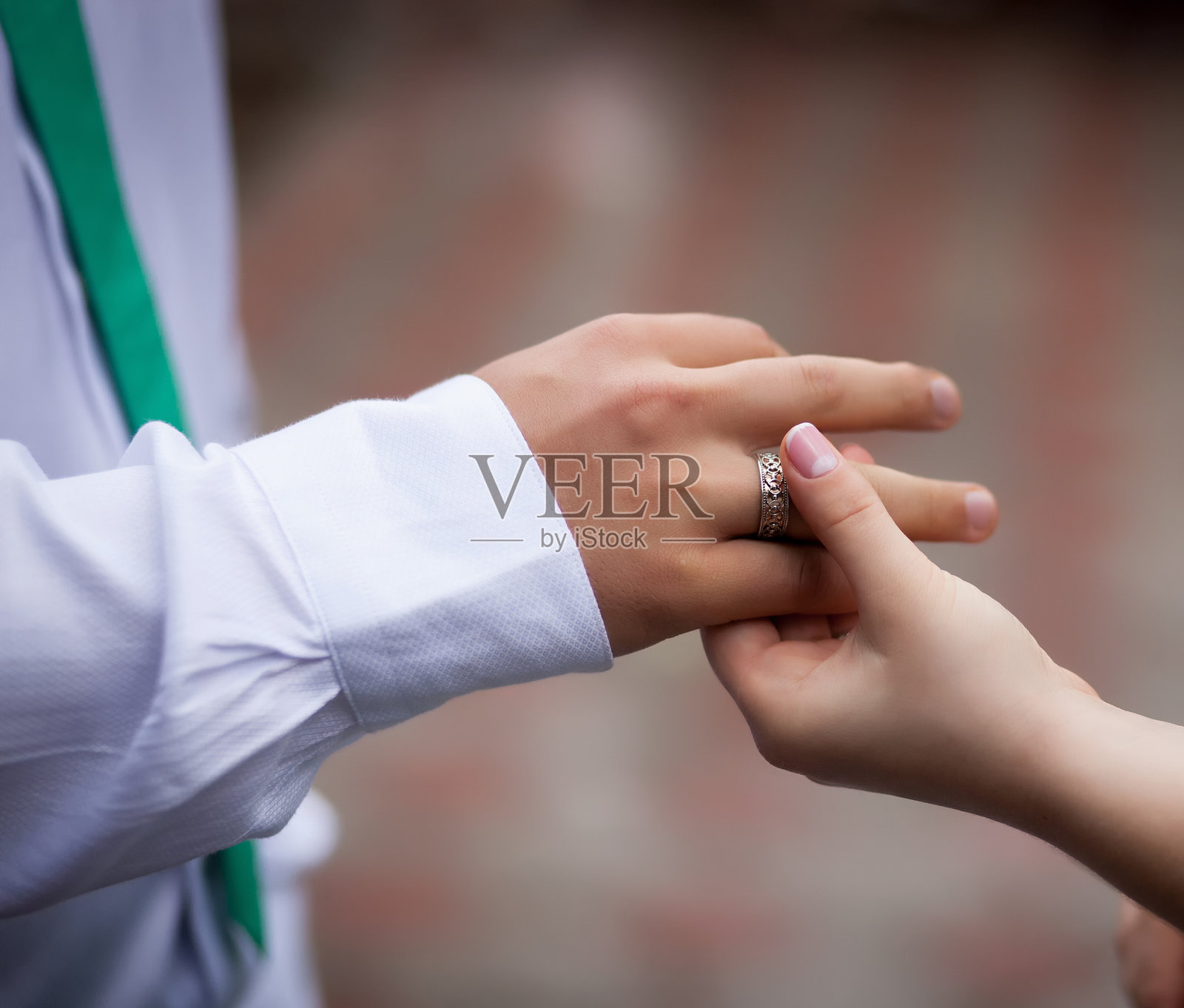 新娘将金色婚戒戴在新郎的手指上。传统的交换婚戒仪式。照片摄影图片