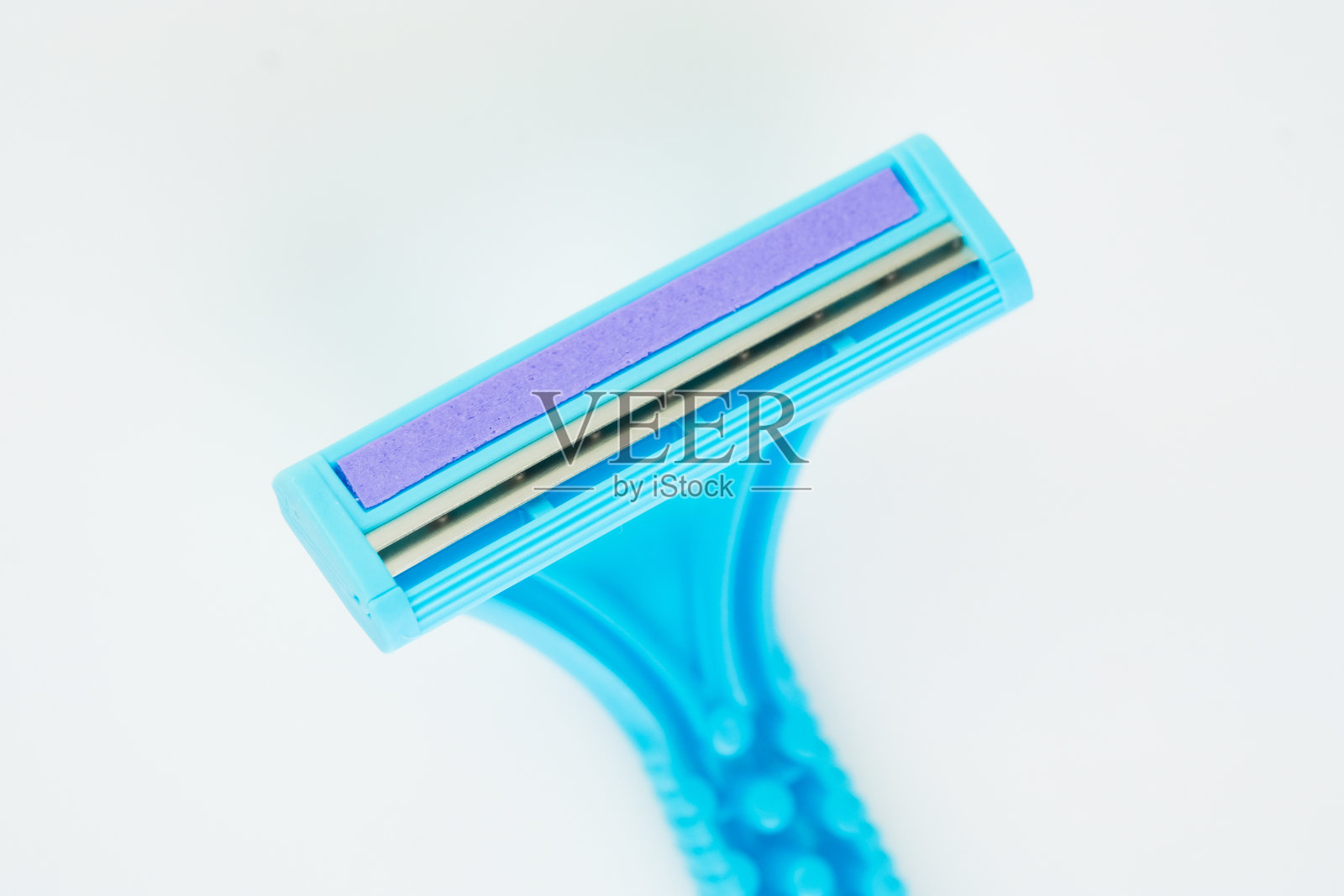 一把带有紫色润滑条的蓝色一次性剃须刀，孤立在白色背景上照片摄影图片