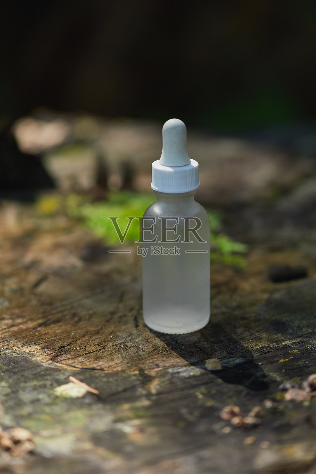 透明滴管瓶放置在木质表面，周围环绕着自然景观照片摄影图片