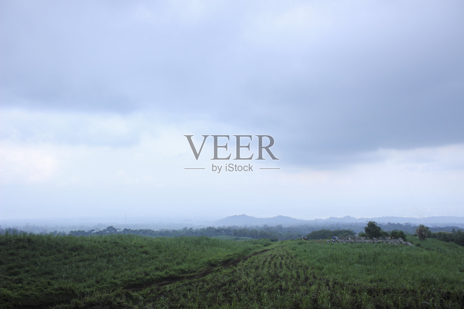 田园诗般的乡村风景，绿意盎然的田野与阴云密布的天空照片摄影图片