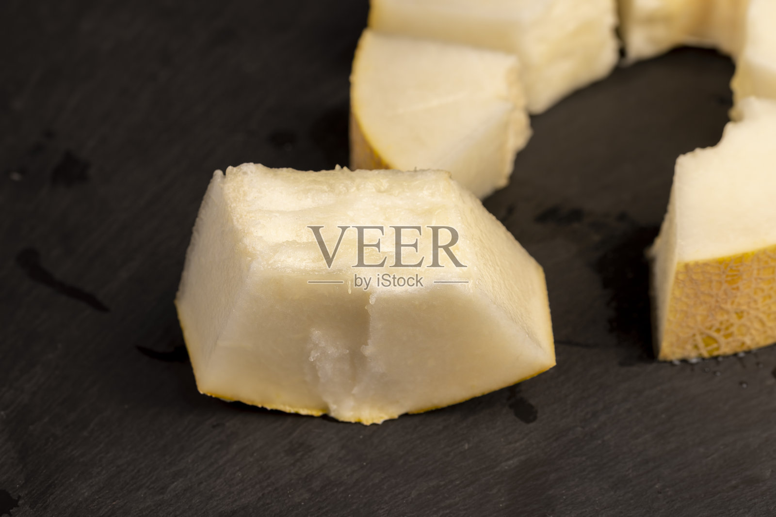 切好的成熟甜美的哈密瓜片放在黑色表面上照片摄影图片