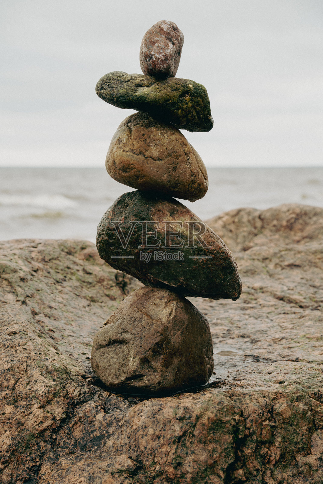 金字塔的石块平衡在岩石上。海洋，冥想的时光。照片摄影图片