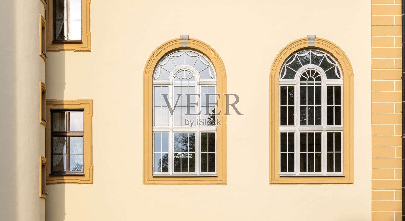 优雅的古典建筑立面，配有对称的拱形窗户，阳光照耀下的黄色墙壁，以及展示复古欧洲风格和历史遗产建筑的装饰性建筑细节照片摄影图片