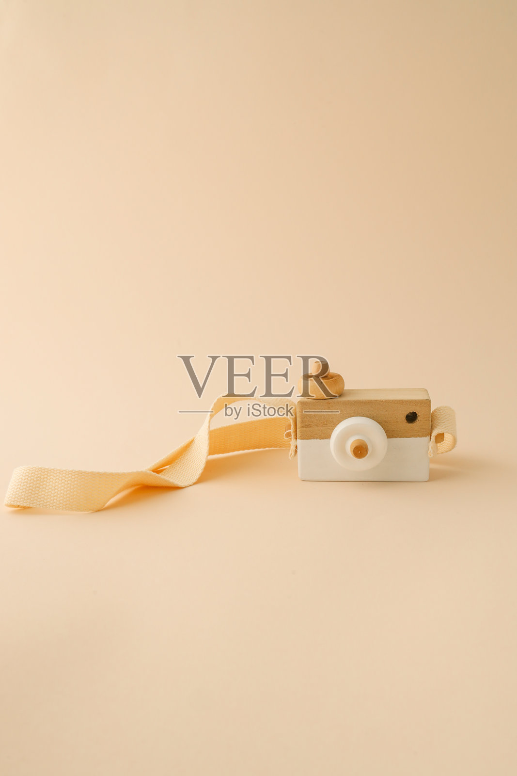木制玩具相机，配有米色带子，背景为简约的浅米色，展现了简单、环保和创意游戏。照片摄影图片