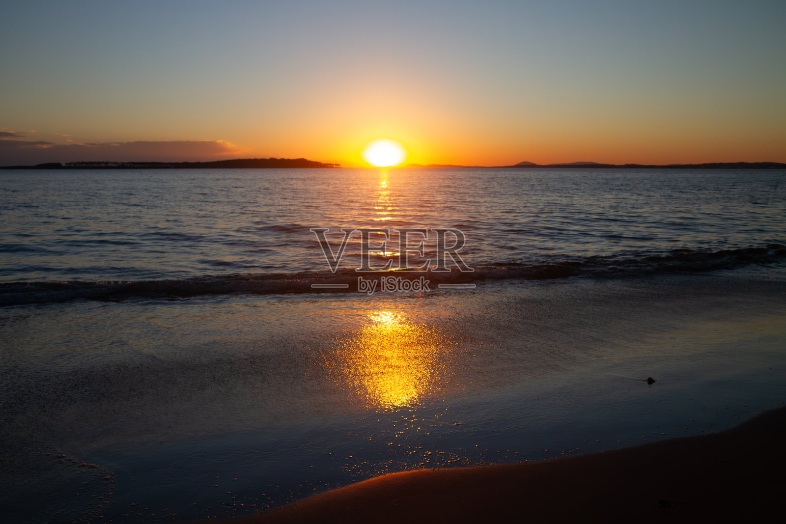 金色日落映照在平静的海浪上，前景是宁静的沙滩。非常适合旅行、自然或宁静风景主题。照片摄影图片