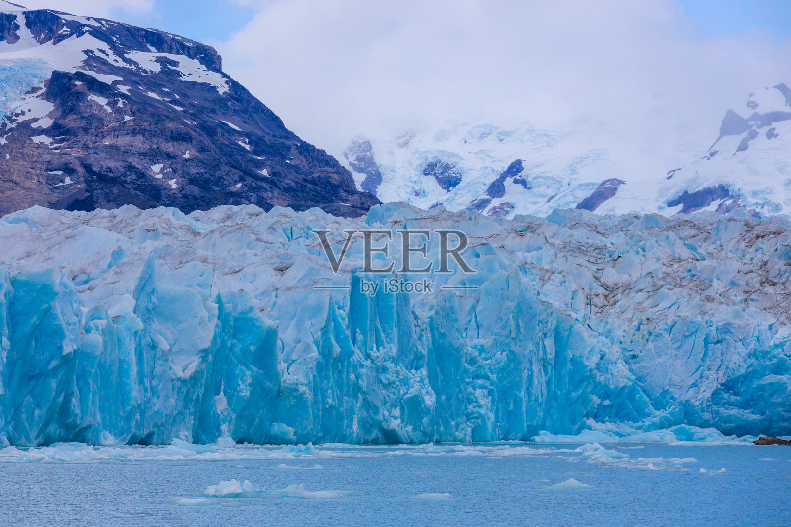 阿根廷巴塔哥尼亚的佩里托莫雷诺冰川。蓝色冰川上巨大的冰塔崩落入冰川湖的水中。照片摄影图片