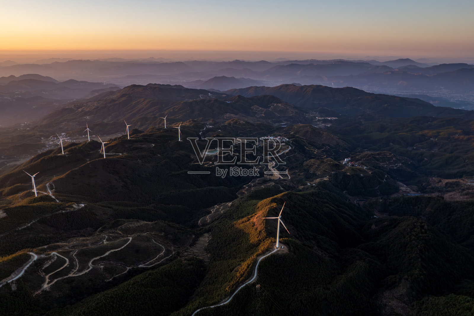 早晨的阳光下，山顶上的风力涡轮机照片摄影图片