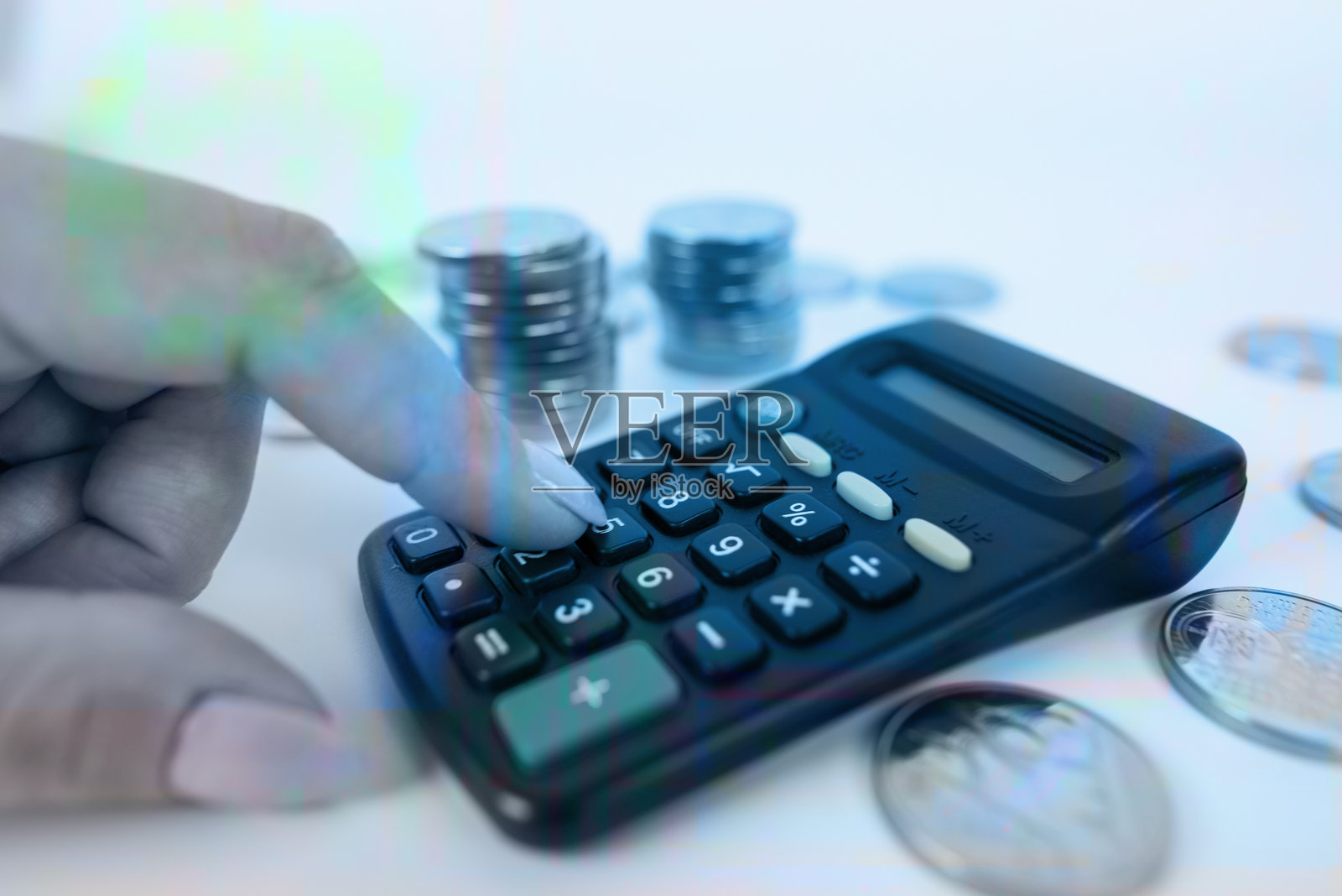 商务女性的手在办公室桌上计算财务报告，旁边有一堆硬币。照片摄影图片