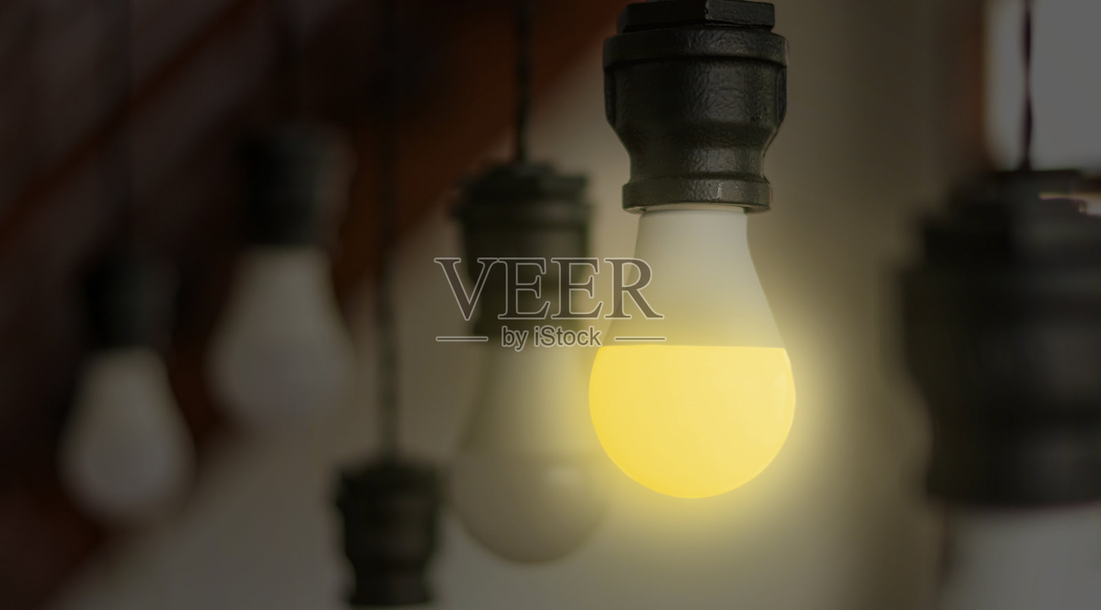 节能概念。手握着新款发光二极管（LED）灯泡，灯光亮起，模糊的螺旋紧凑型荧光灯（CFL）灯泡在后面留有空白空间。照片摄影图片