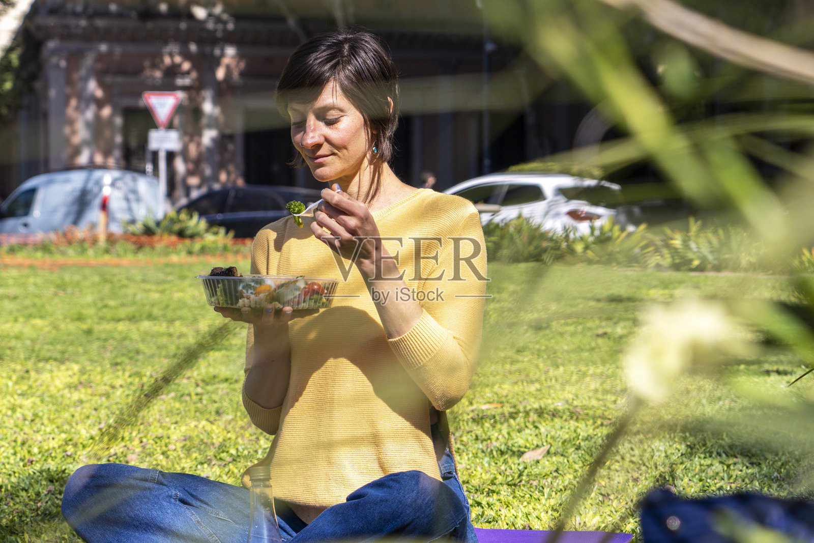 一位健康的女性在阳光明媚的日子里享受公园里的新鲜沙拉。照片摄影图片