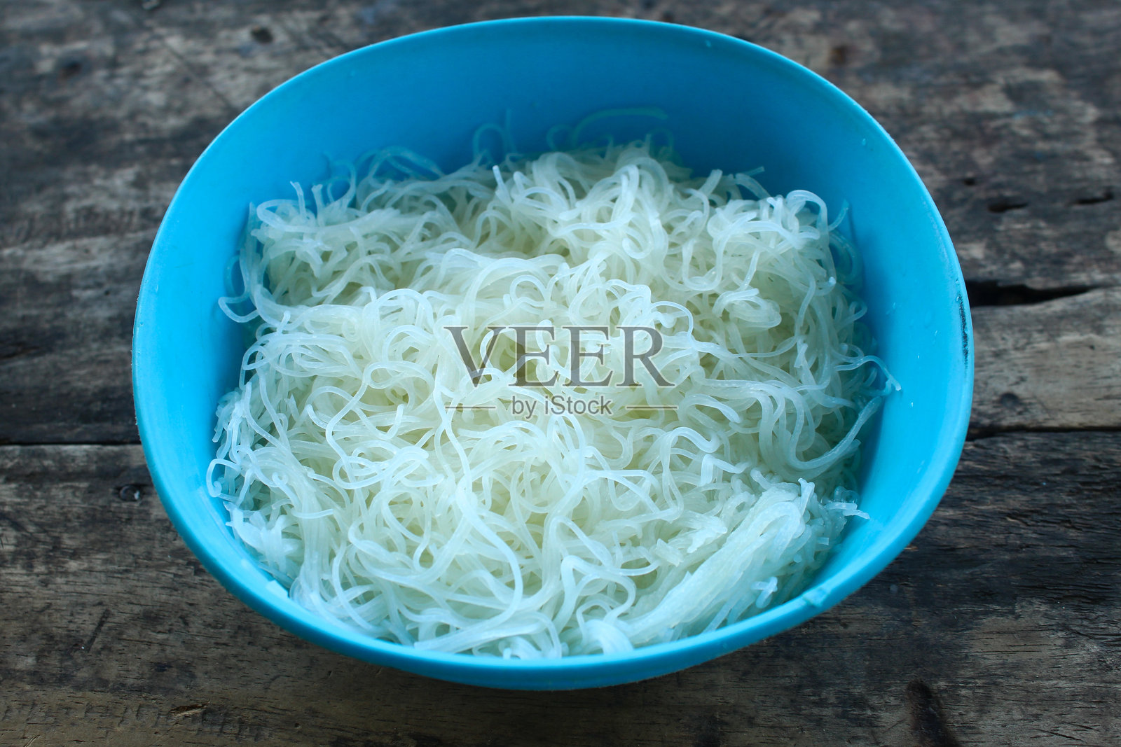 蓝色碗中的白色湿米粉。白色米粉的特写。照片摄影图片