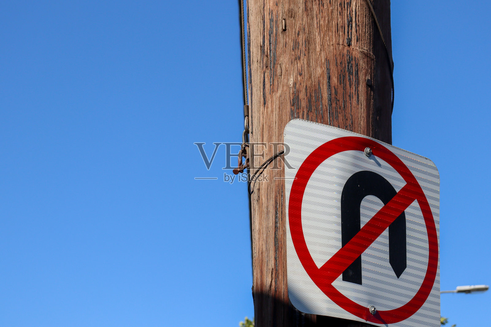 蓝天背景下木柱上的禁止掉头标志照片摄影图片