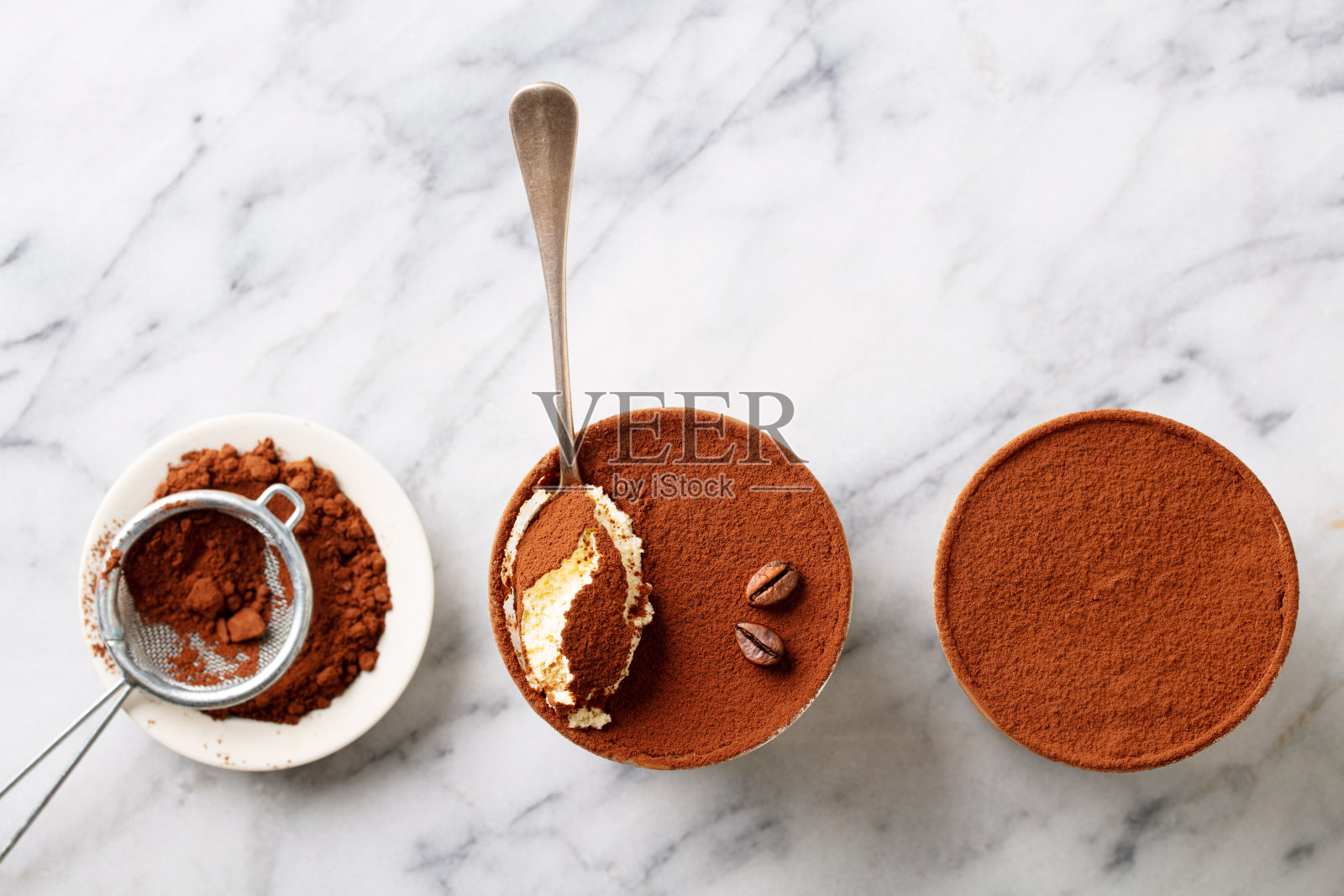 杯中提拉米苏甜点和碗中的可可粉。大理石背景。留白。俯视图。照片摄影图片