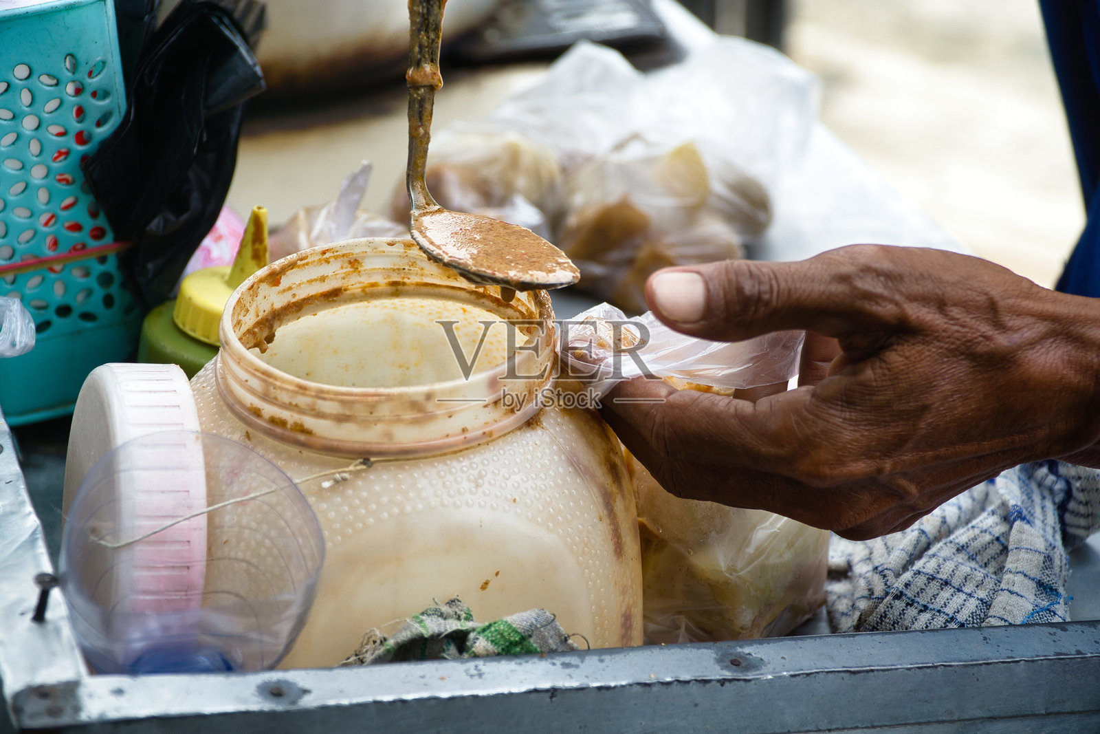 街头小贩为顾客倒花生酱在新鲜的烧卖上，这是一种典型的印尼小吃，由淀粉制成并在沸水中蒸熟。照片摄影图片