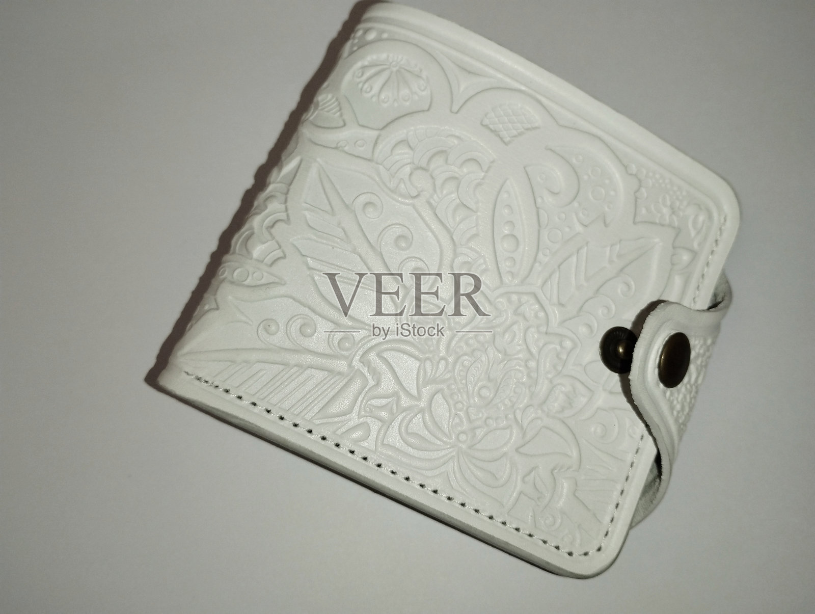 白色女性钱包，用于存放银行卡和现金，背景为白色。皮革钱包带有装饰性压花。照片摄影图片