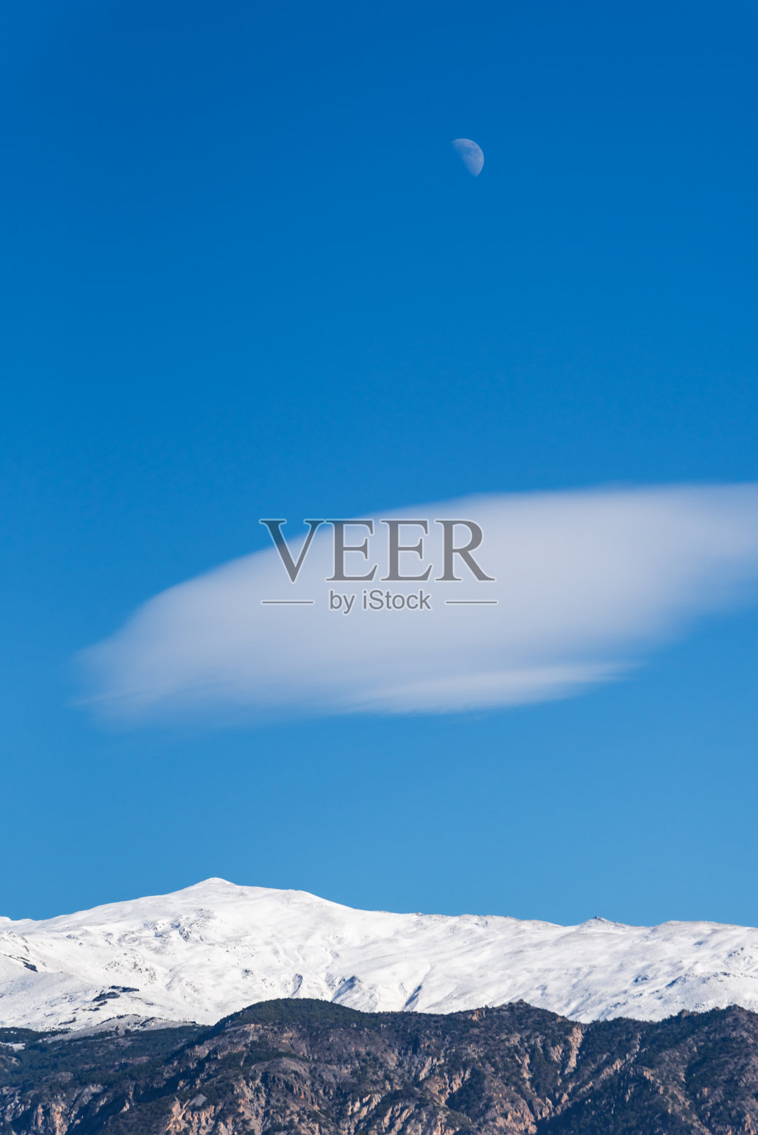 格拉纳达的内华达山脉，维莱塔峰上方有一个透镜云和月亮，安达卢西亚。照片摄影图片