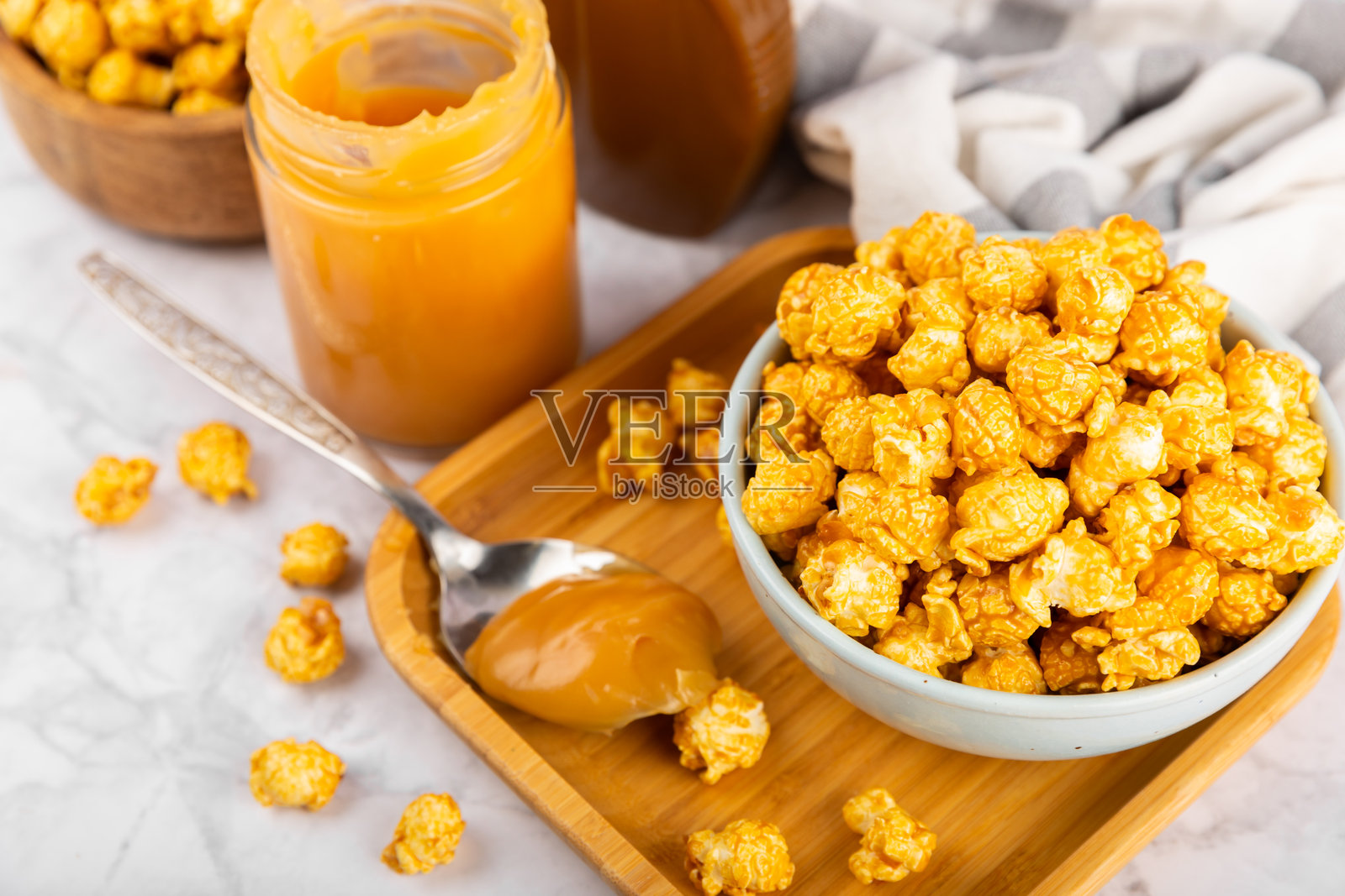 甜美的焦糖爆米花放在木质背景的碗中。咸焦糖爆米花。焦糖酱。特写。装饰。留白。照片摄影图片