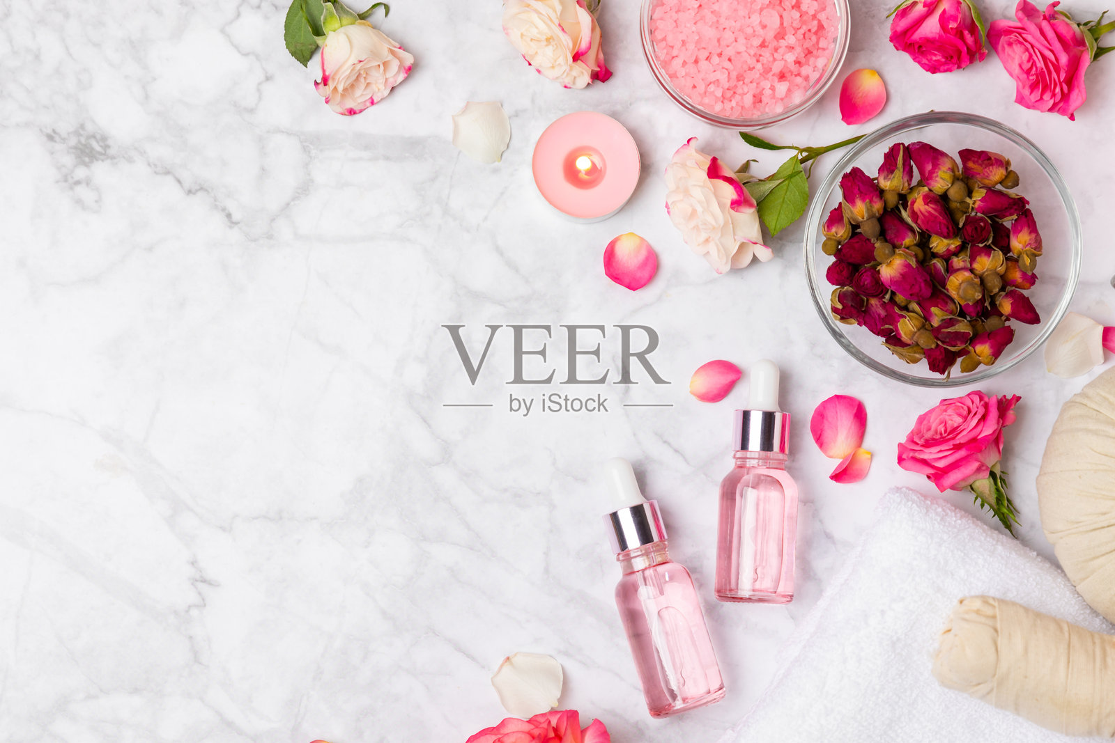 玫瑰精油在纹理背景上。玫瑰和一瓶玫瑰香水。芳香疗法治疗。美容概念。水疗程序。天然有机油。抗压、排毒放松。文本位置。照片摄影图片