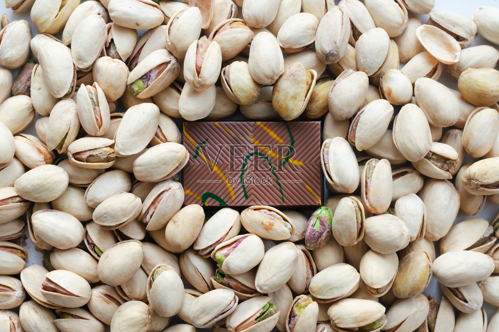 一块带有开心果酱和奶酪填充的库奈法的迪拜巧克力，背景是开心果。流行的美食概念。横向构图。照片摄影图片