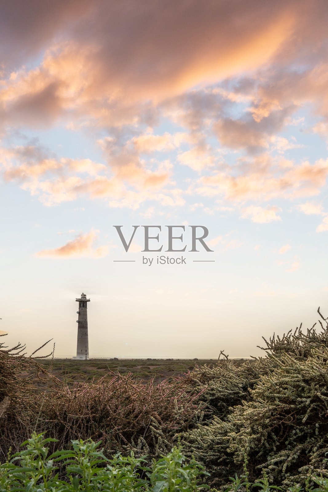 自然保护区日落时的灯塔。在摩罗哈布尔，富埃特文图拉，加纳利群岛，西班牙的轻微沙尘暴中灯塔。照片摄影图片