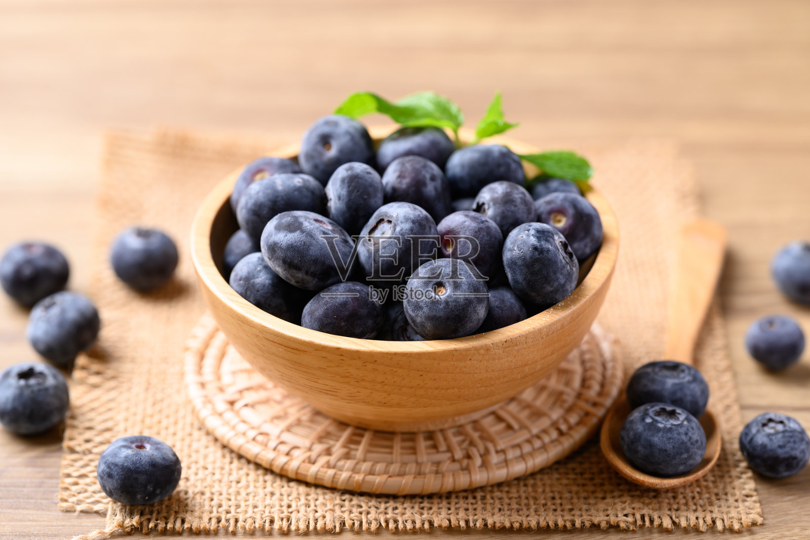 木桌上的木碗里装着蓝莓，健康的水果，食品原料照片摄影图片