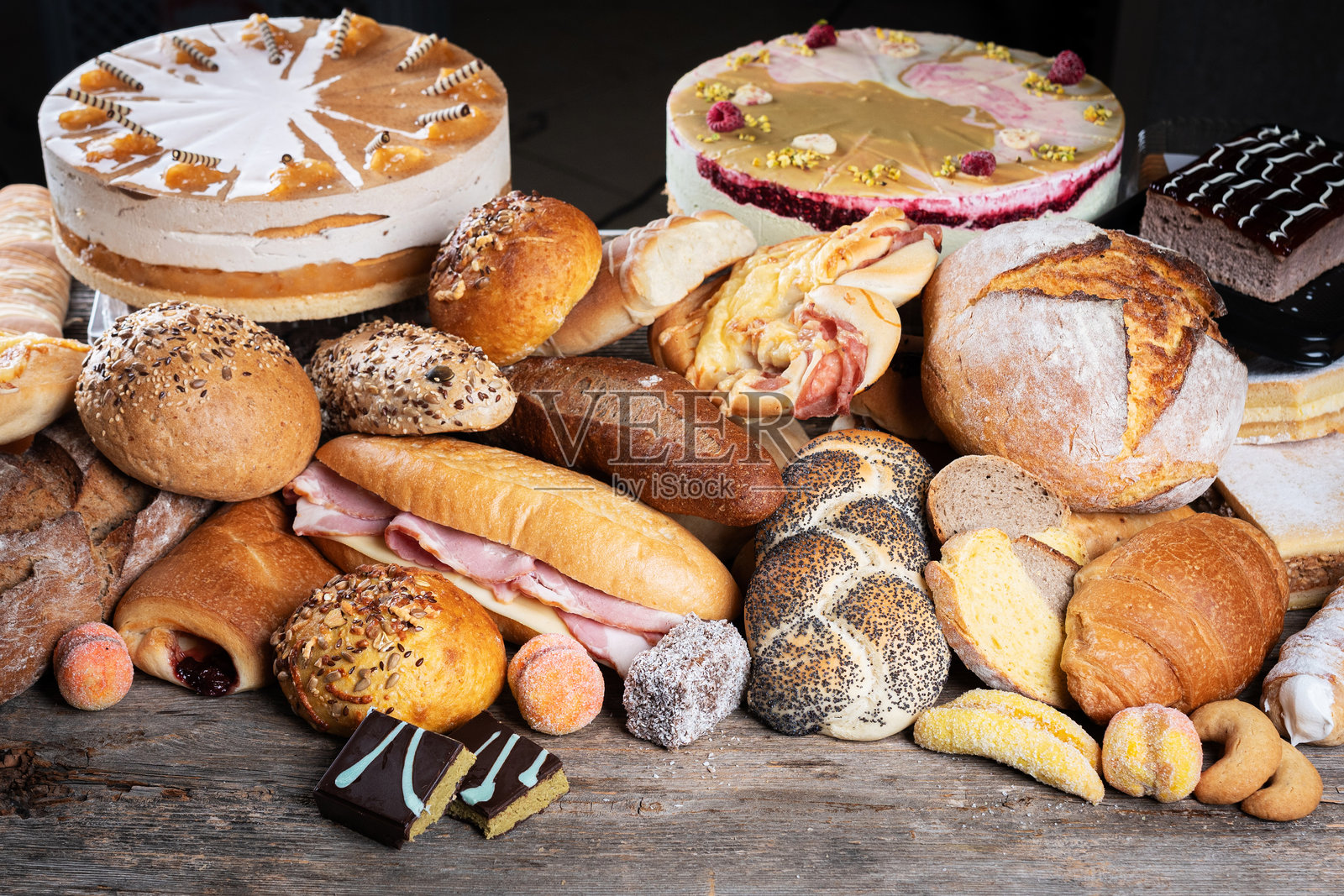 各式新鲜面包和糕点，包括卷、可颂和小圆面包，陈列在一张乡村风格的木桌上照片摄影图片