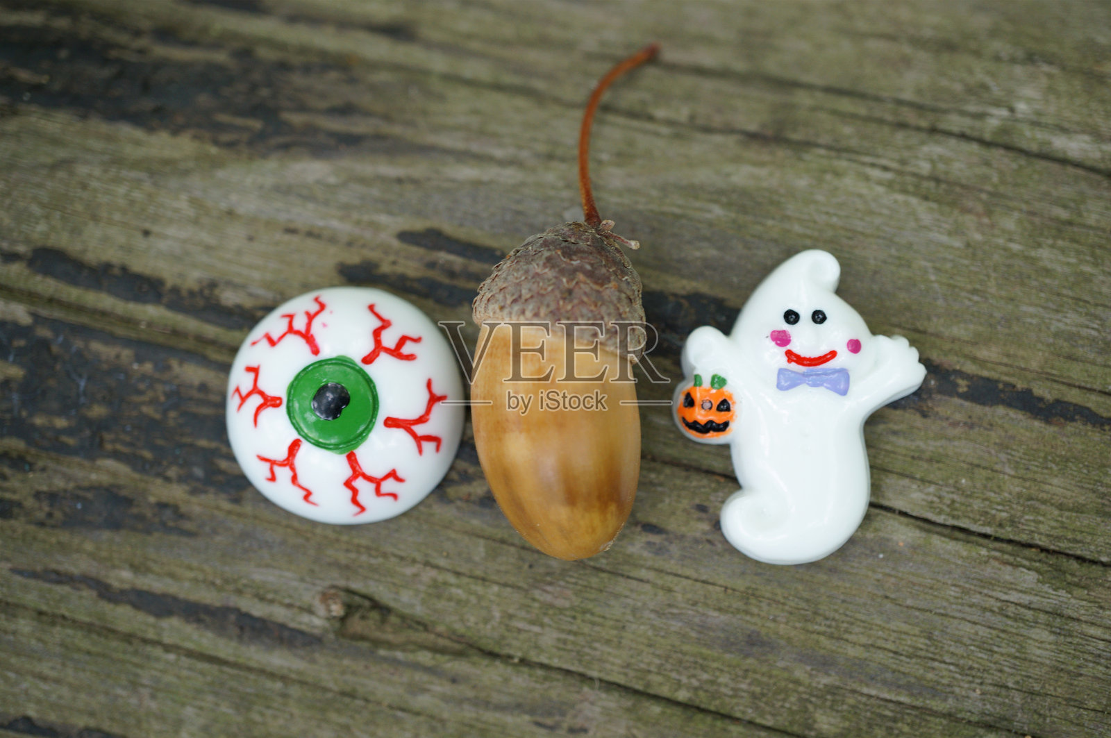 一个玩具鬼魂，手里拿着一个橡果和一个玩具眼睛。照片摄影图片