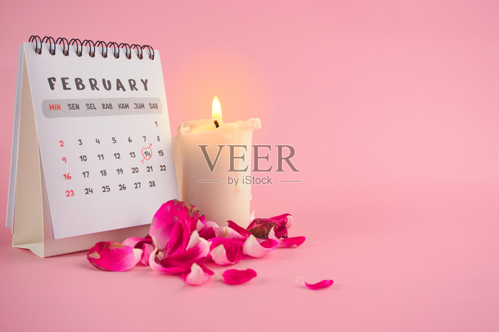 情人节日历，白色蜡烛和玫瑰花瓣置于粉色背景上照片摄影图片