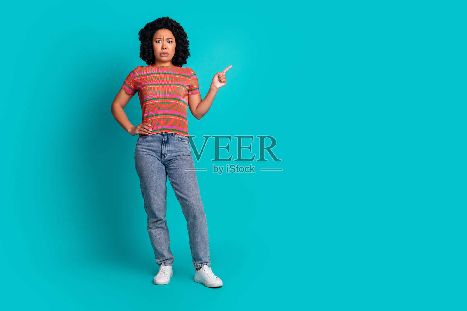 漂亮年轻女孩用手指指向空白处，背景为青绿色。照片摄影图片