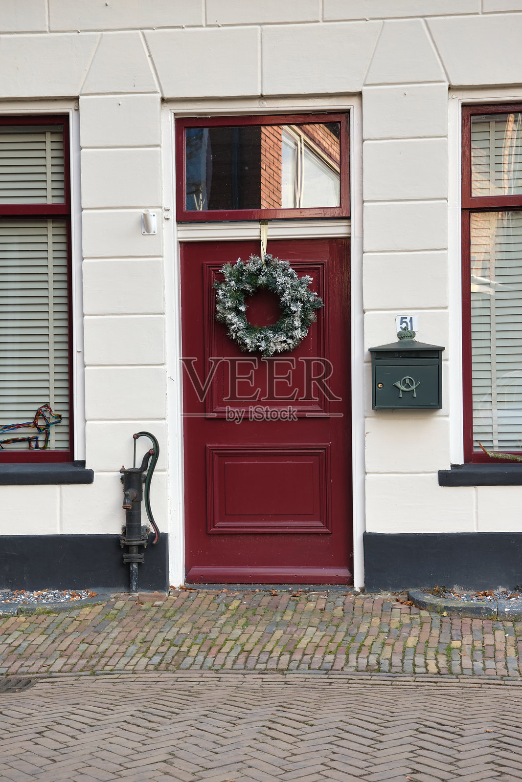荷兰坎彭的历史白色外立面,红色门和花环照片摄影图片