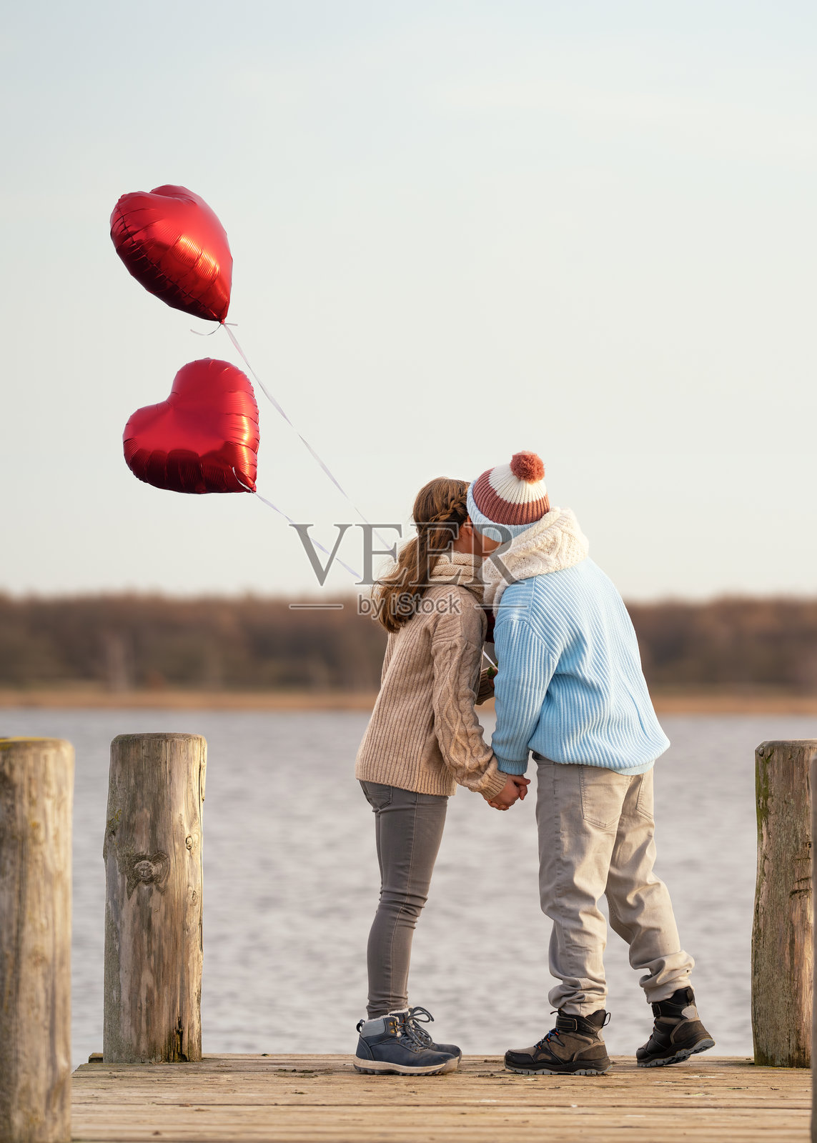 可爱的情侣孩子，男孩在木栈道上亲吻他的女朋友照片摄影图片