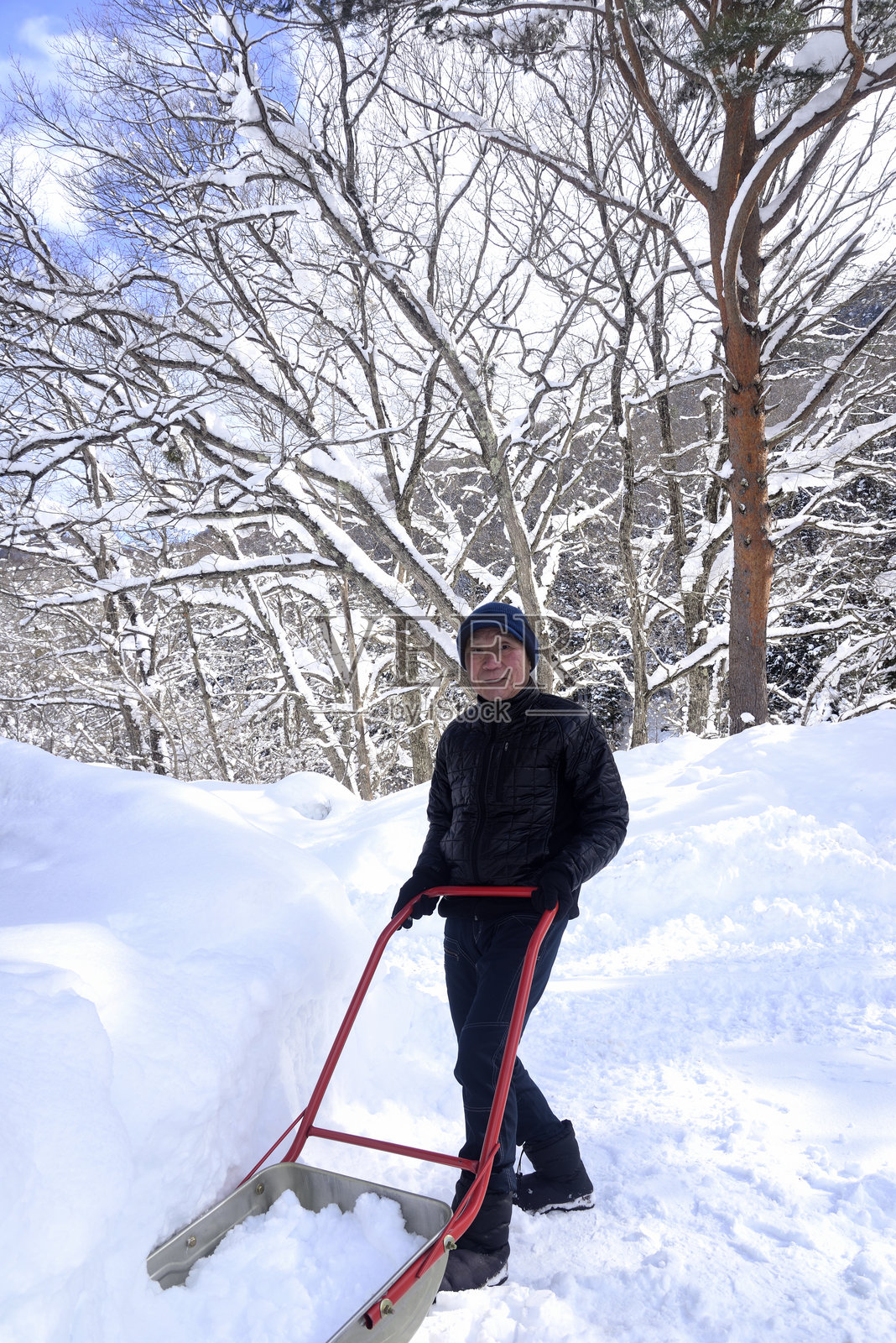 一位老人正在雪地里清理积雪照片摄影图片