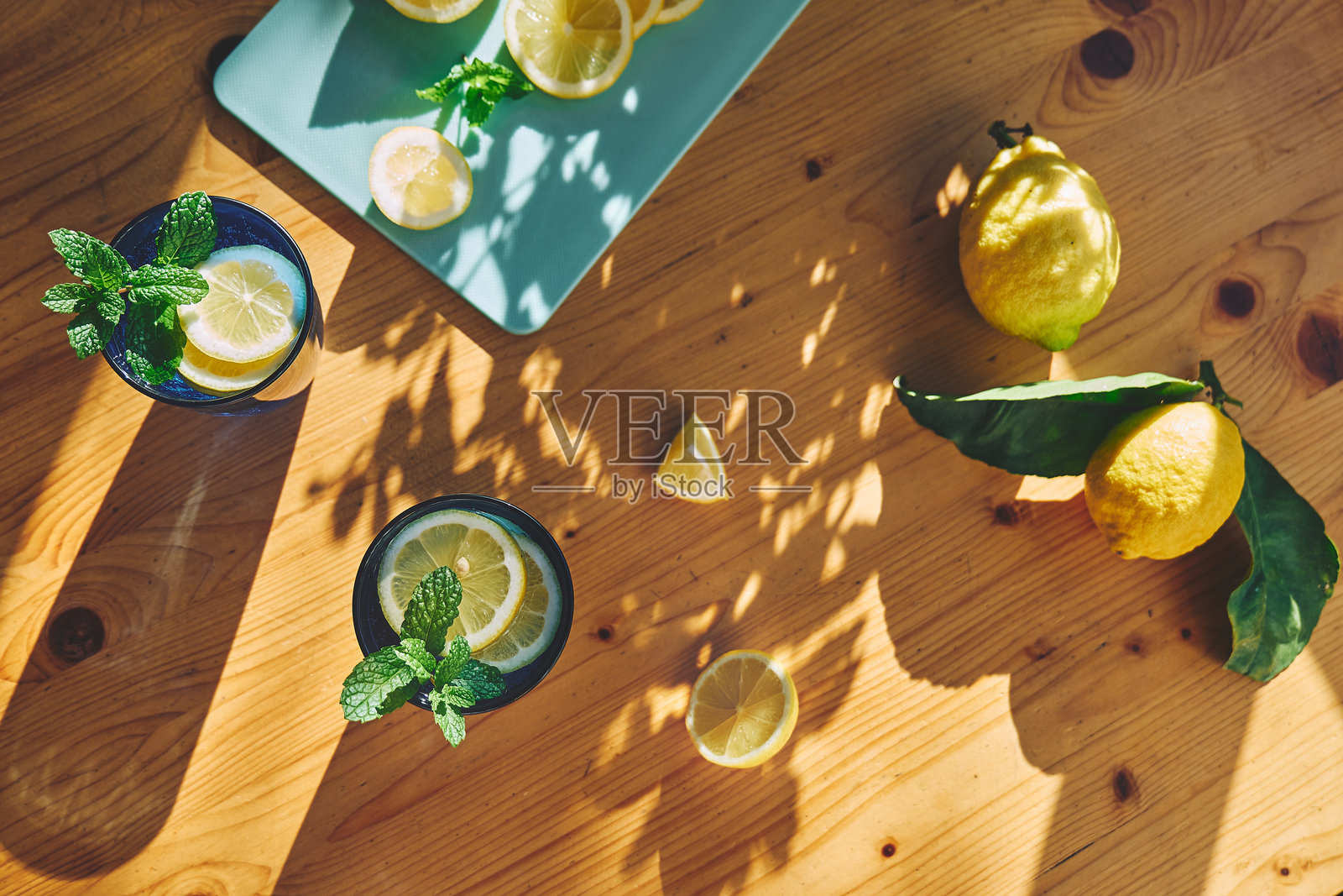 夏季清爽的柠檬水饮料，配有薄荷、冰块和柠檬片，放在木桌上。新鲜健康的冷柠檬饮品。柠檬浸泡水。照片摄影图片