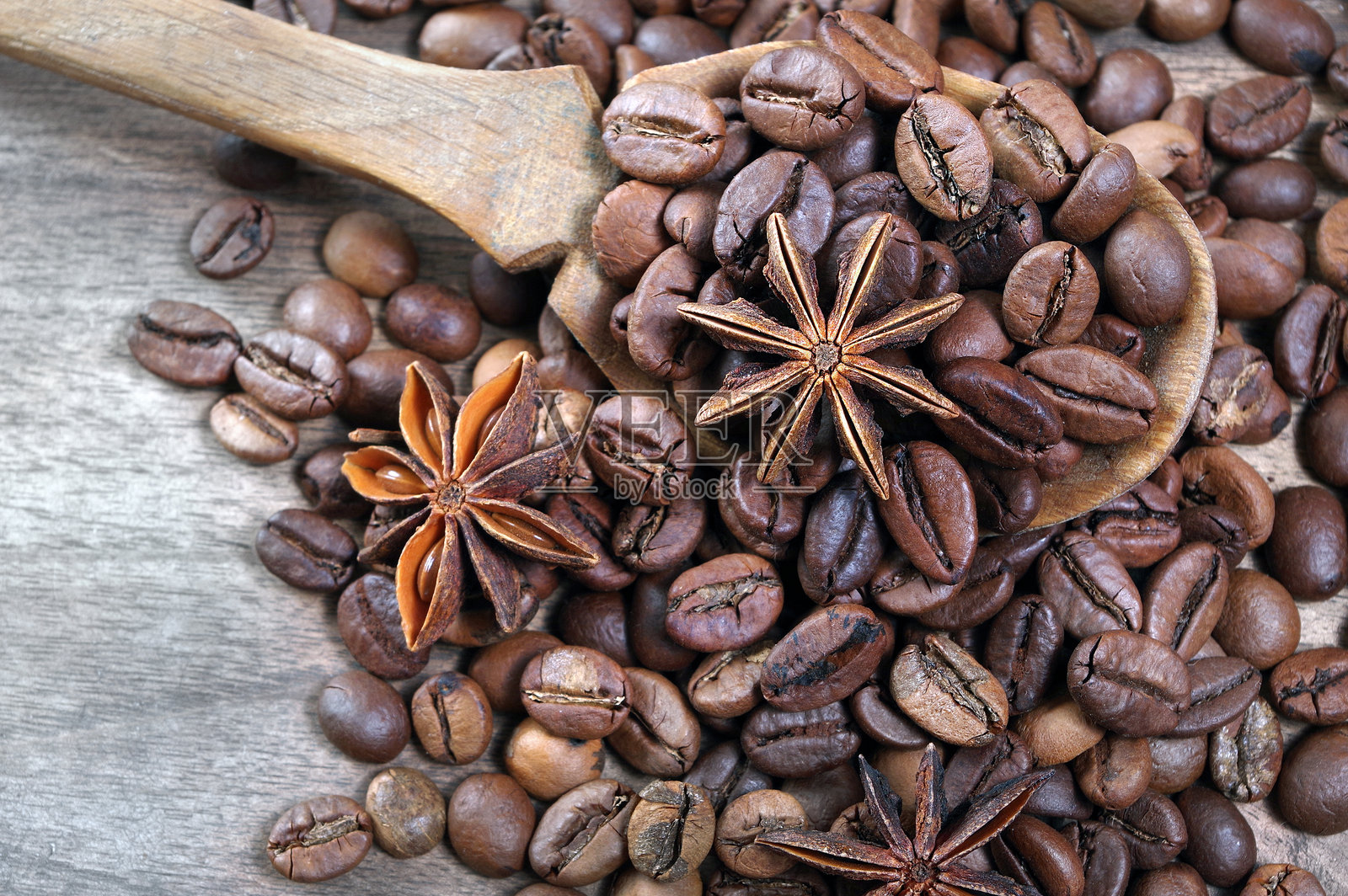 勺子里的咖啡豆。烘焙咖啡豆与八角星在木桌上。咖啡与香料。俯视图。照片摄影图片