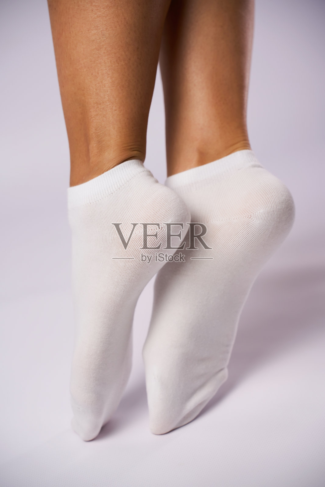 女性的脚穿着白色棉袜，背景为白色，留有空白空间。女人的腿部特写，穿着新袜子。照片摄影图片