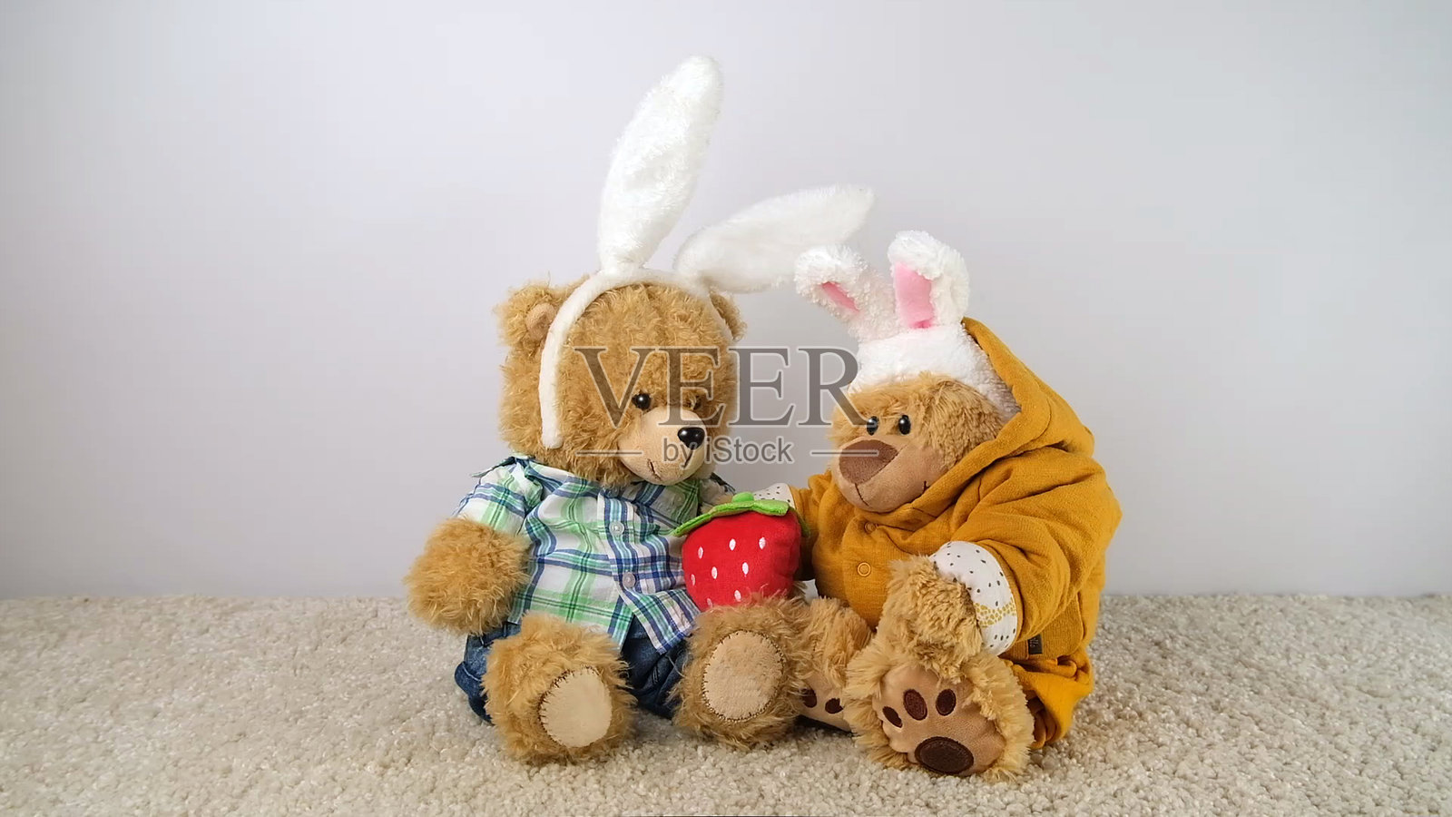 两个戴着兔耳朵的泰迪熊和草莓。照片摄影图片