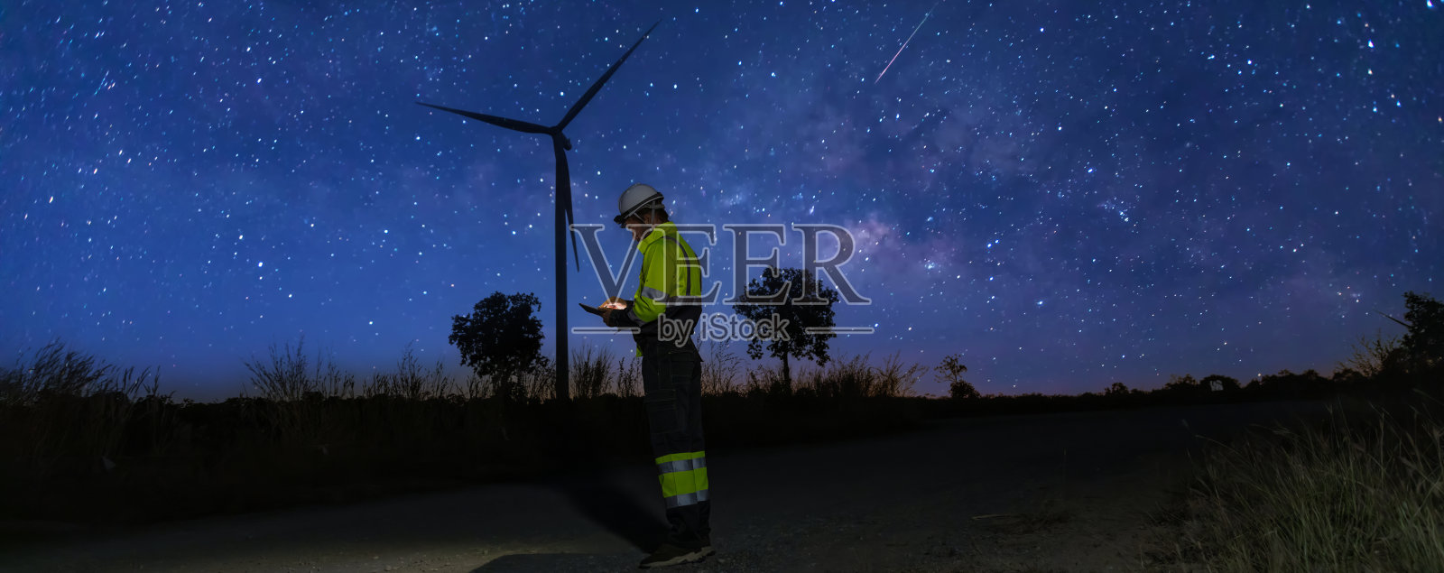 调查团队在夜间进行未来替代能源的检查以确保安全。工程师们在银河背景下对风力涡轮机进行勘测和检查。风力涡轮机可再生能源技术。照片摄影图片
