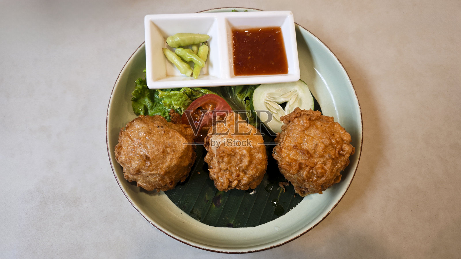 脆皮豆腐饼配新鲜蔬菜和甜辣酱，盛放在香蕉叶衬里的盘子上照片摄影图片