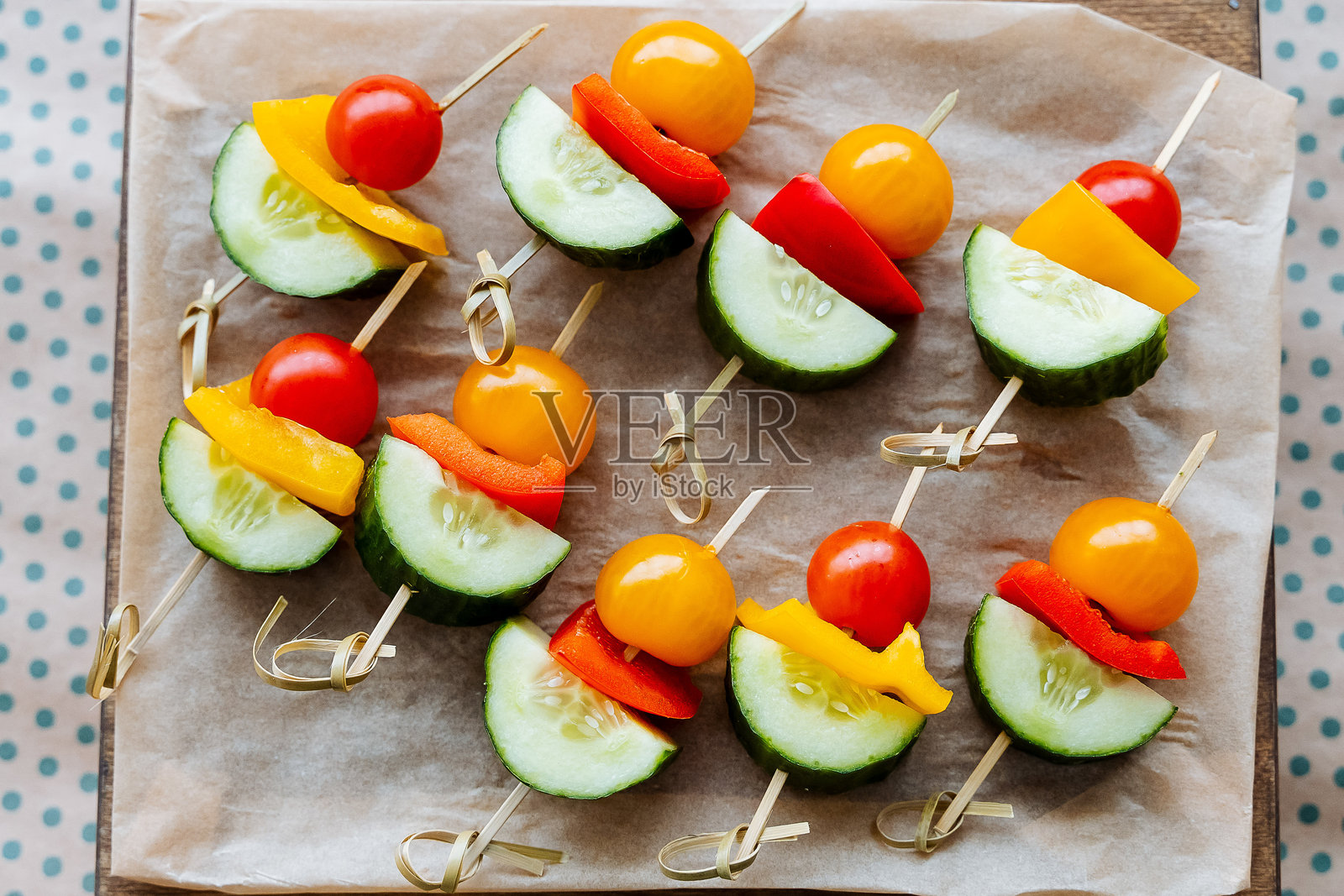 精美摆放的五彩蔬菜串，包括新鲜的黄瓜、成熟的西红柿、鲜艳的辣椒和阳光般的黄色辣椒，适合任何聚会或餐点。照片摄影图片