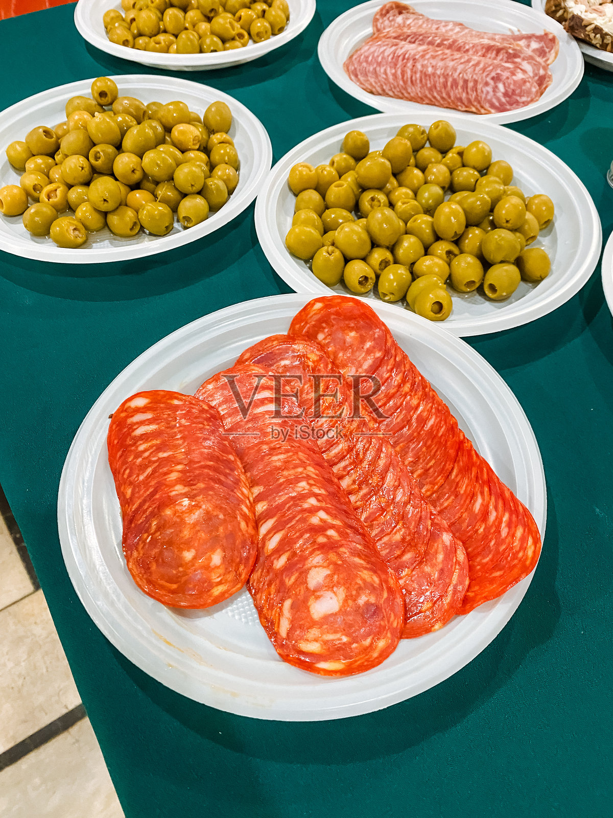 桌子上摆放着几盘美味的食物，包括咸香的西班牙香肠、咸味橄榄和酥脆的培根，为大家共同享用创造了一个愉快的盛宴。照片摄影图片