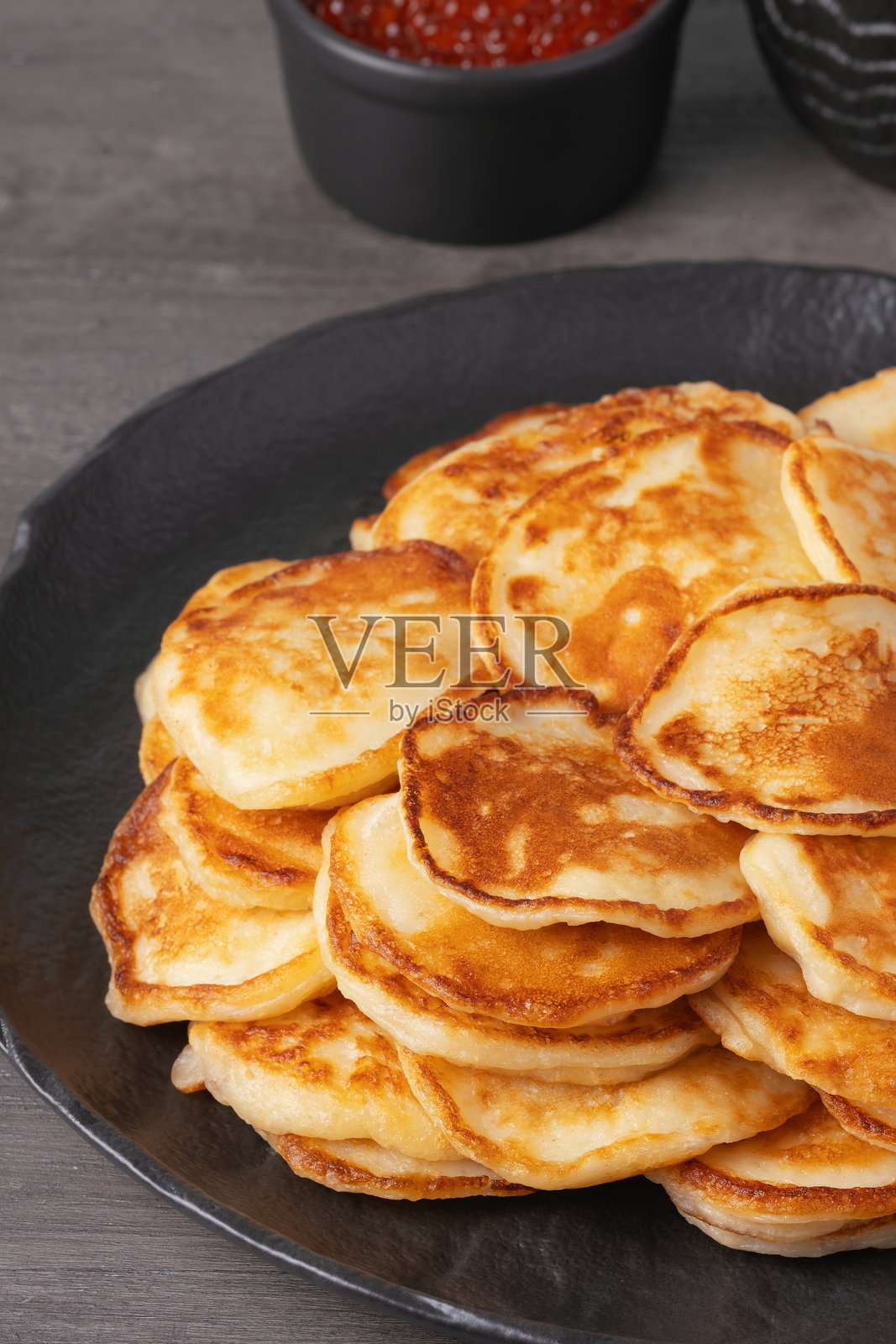 美味的金色煎饼堆叠在乡村风格的桌子上，配有奶油和鱼子酱照片摄影图片